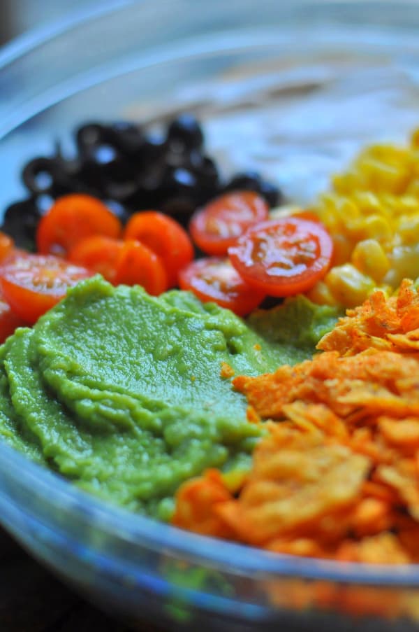 This easy Taco Salad is a quick recipe and is layered with Doritos, ground beef and your favorite taco toppings like corn, cilantro, Nacho Cheese doritos, guacamole, tomatoes, sour cream.