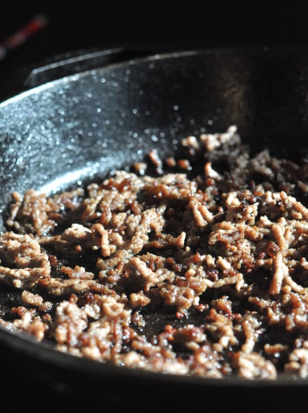 This easy Taco Salad is a quick recipe and is layered with Doritos, ground beef and your favorite taco toppings. Cast iron pan making browned meat.