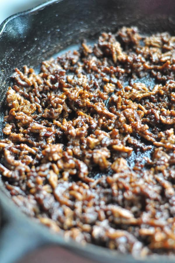 This easy Taco Salad is a quick recipe and is layered with Doritos, ground beef and your favorite taco toppings. Cast iron pan making browned meat.