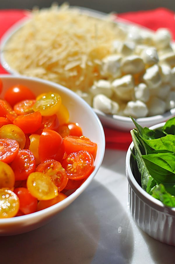 Caprese pasta salad ingredients of mozzarella, tomatoes, and basil.