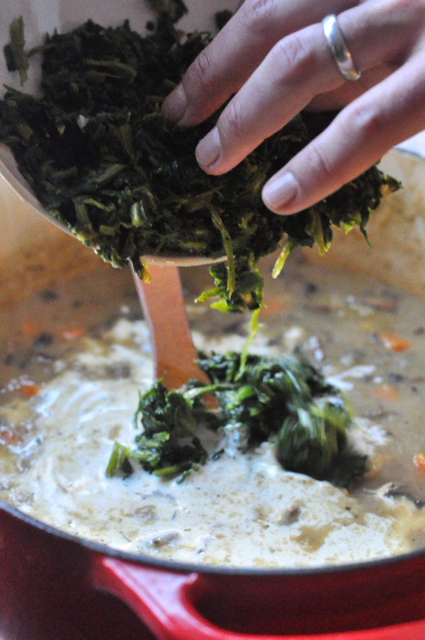 spinach going into a soup pot of vegetarian wild rice soup